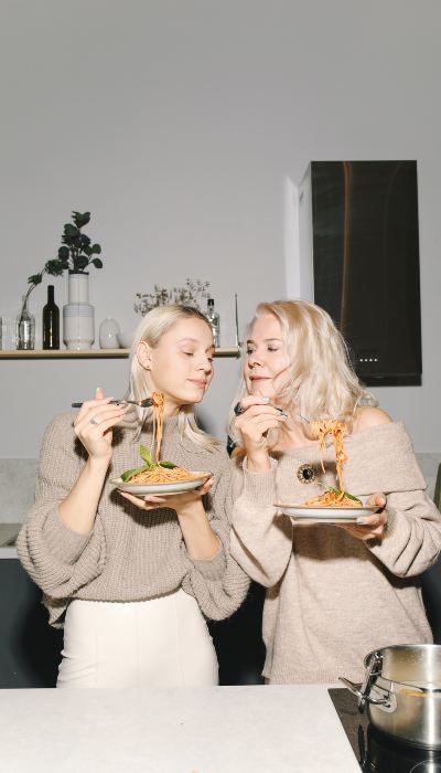 Two girls are eating pasta